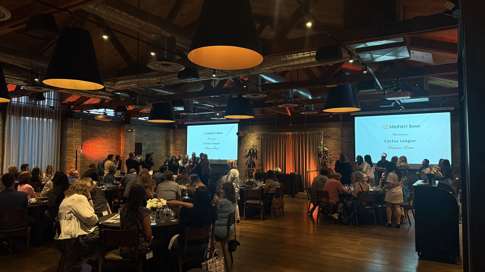 Guests gathered for a MidFirst Bank All-Star employee event with presentation screens and room lighting